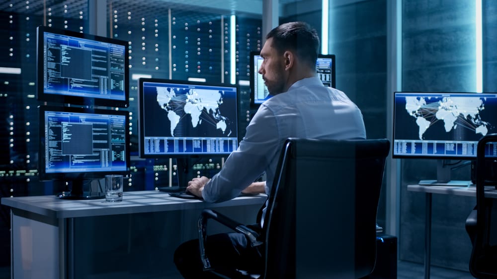 A man using a computer with multiple monitors