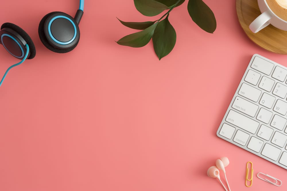 A workplace with a laptop, headphones, and a cup