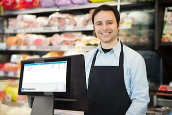 Man at grocery store with a point-of-sale system and a customer-facing display.